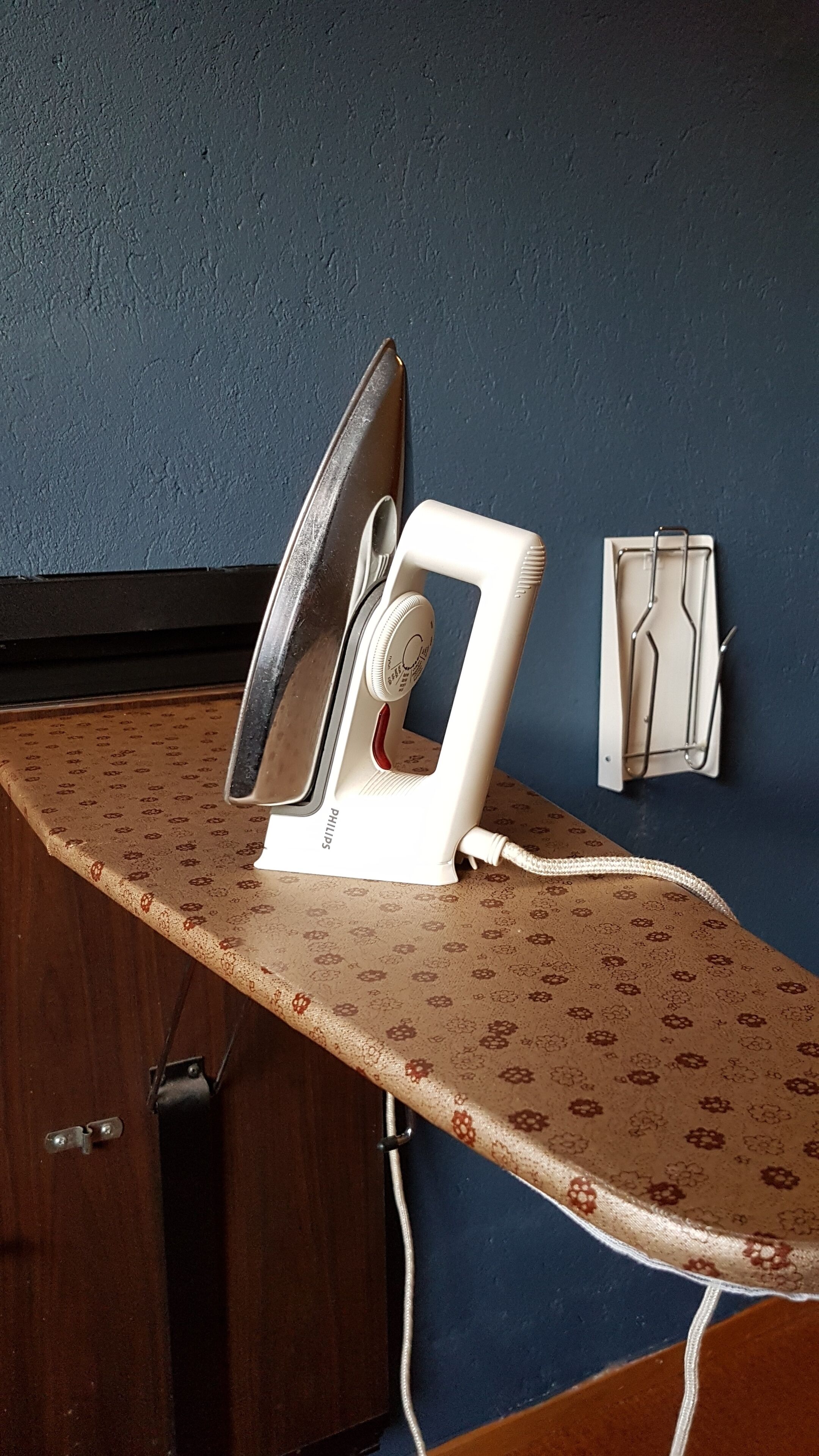 An ironing board with an iron and a Philips appliance on a patterned countertop.