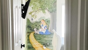A hallway with a wall mural of a fairy tale scene, a white chair, and a flat-screen TV mounted on the wall. - Las Palmas Resort #1627 | All-Inclusive Amenities (Saint George)