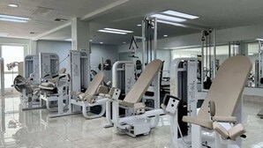 A gym with various exercise machines, a large mirror wall, and a tiled floor. - Las Palmas Resort #1627 | All-Inclusive Amenities (Saint George)