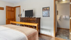 Ein Schlafzimmer mit einem Bett, einem Schminktisch, einem Fernseher und einer Tür zu einem Badezimmer.