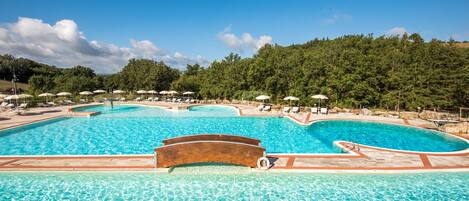 Alberca al aire libre, sombrillas en la alberca y camastros