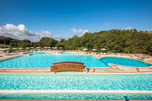 Una piscina al aire libre, sombrillas, sillones reclinables de piscina