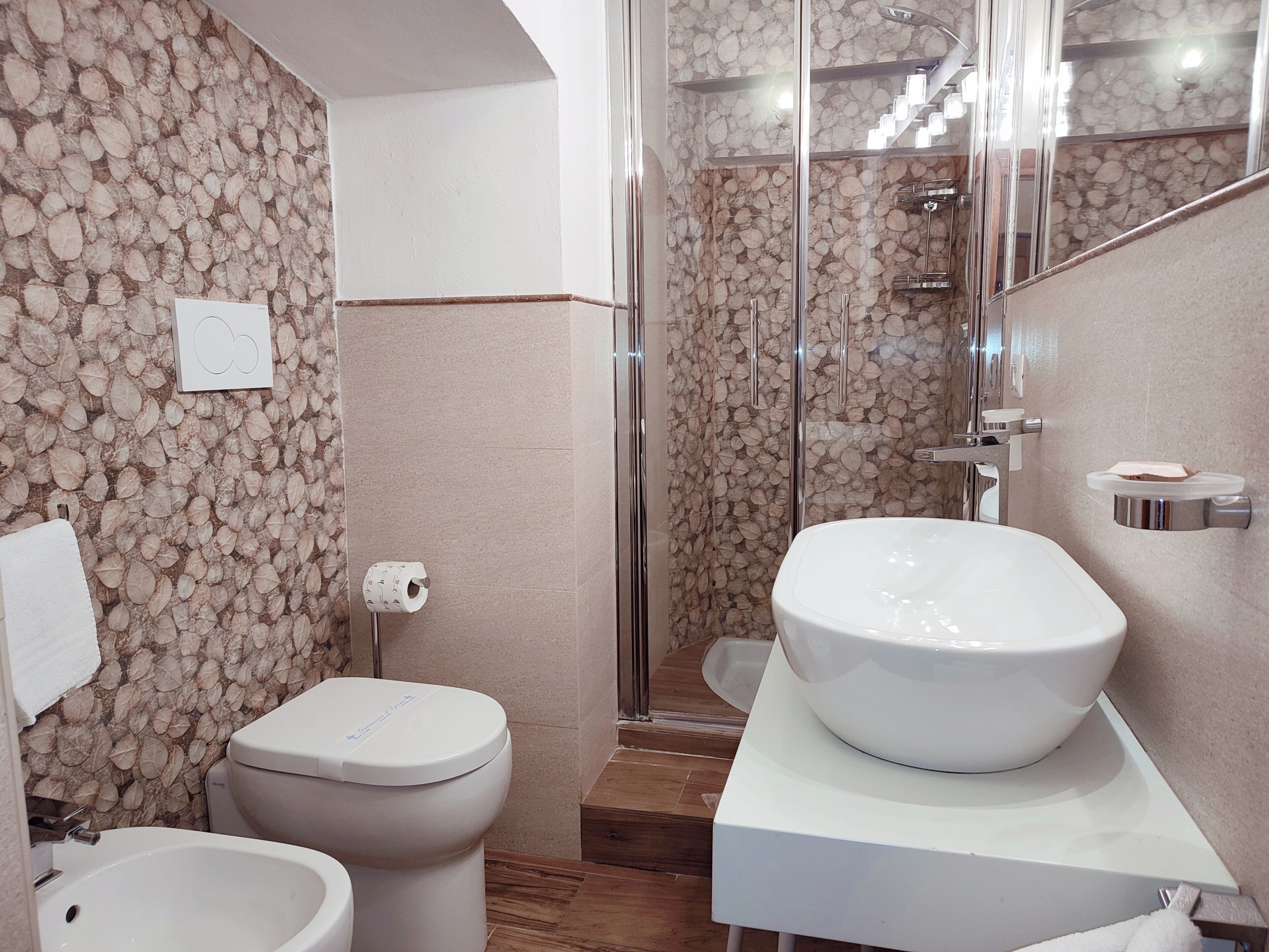 A bathroom with a toilet, bidet, and a large sink on a white countertop.