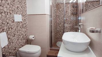 A bathroom with a toilet, bidet, and a large sink on a white countertop.