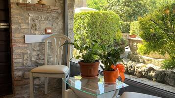 Un espace extérieur accueillant avec une table en verre, deux chaises et des plantes en pot.