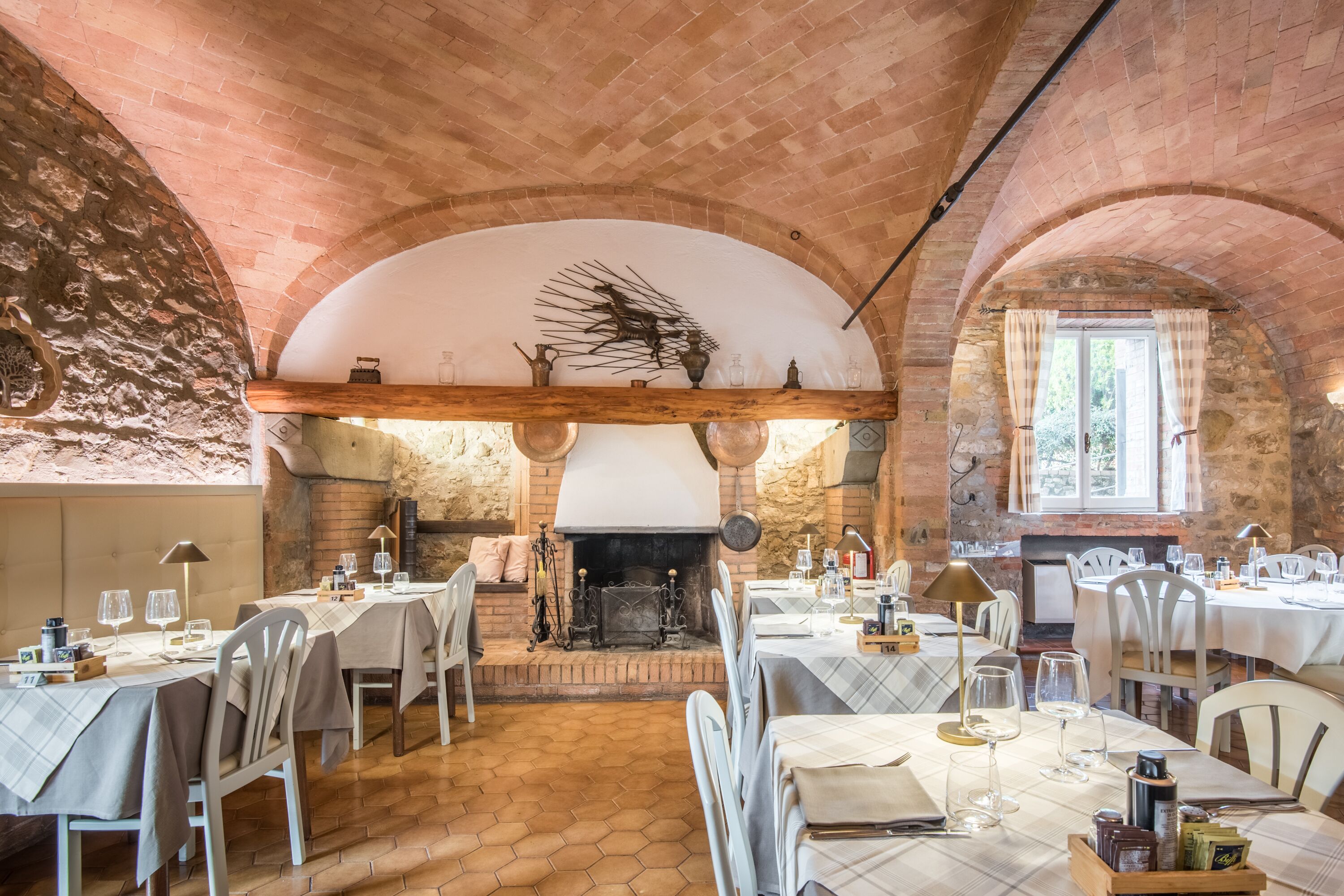 A restaurant with brick arches, a fireplace, and tables set for dining.