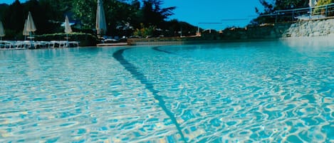 Una piscina al aire libre, sombrillas, tumbonas