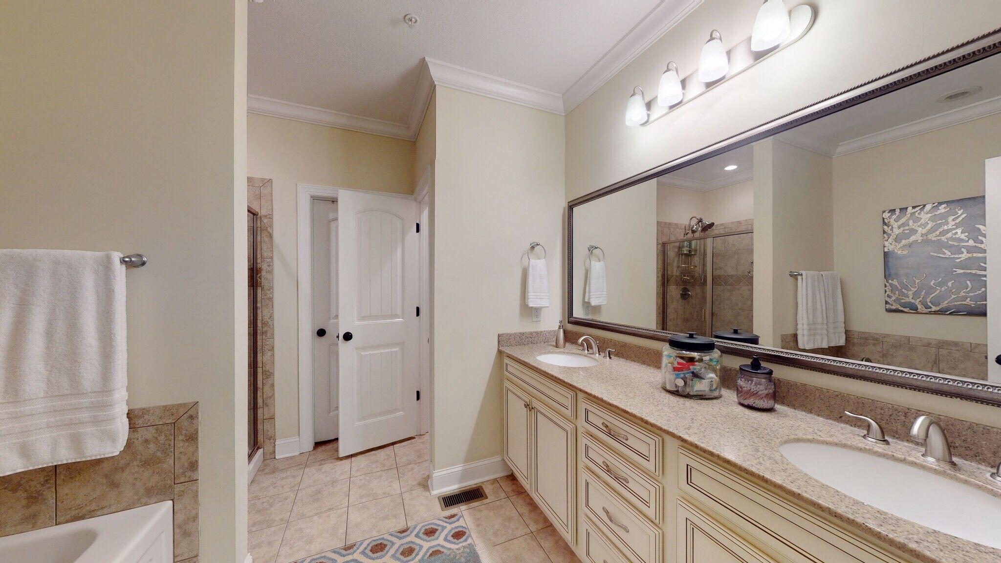 A bathroom with two sinks, a large mirror, and a shower.