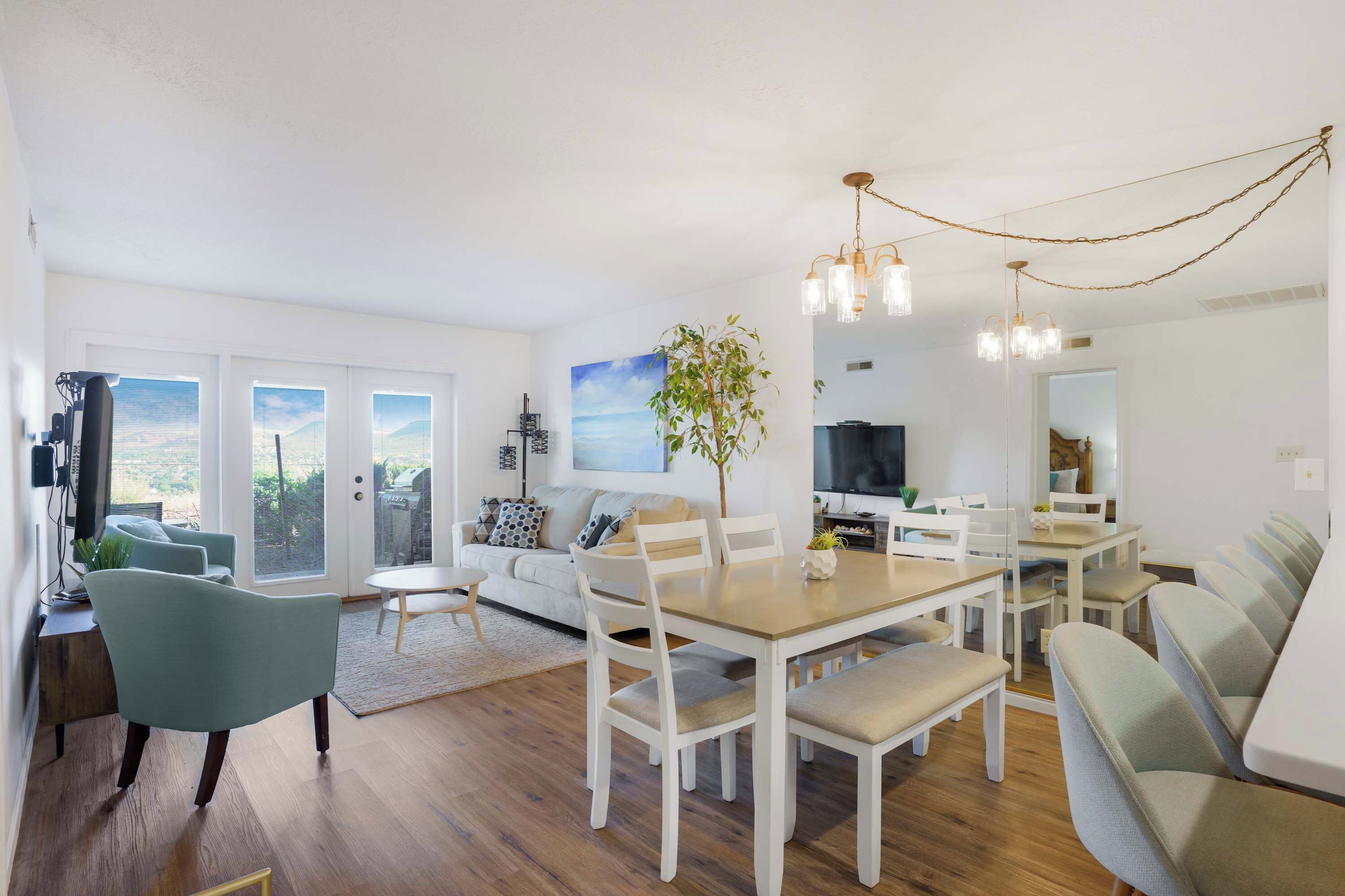A modern living room with a dining area, a TV, and a large window with blinds.