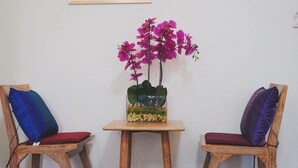 Two wooden chairs with cushions, a small table, and a potted orchid plant. - HP House Cafe' (Chiang Mai)