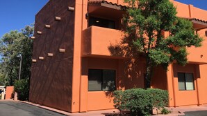 Un bâtiment à deux étages, doté d’un toit plat, d’un balcon et d’un arbre devant.