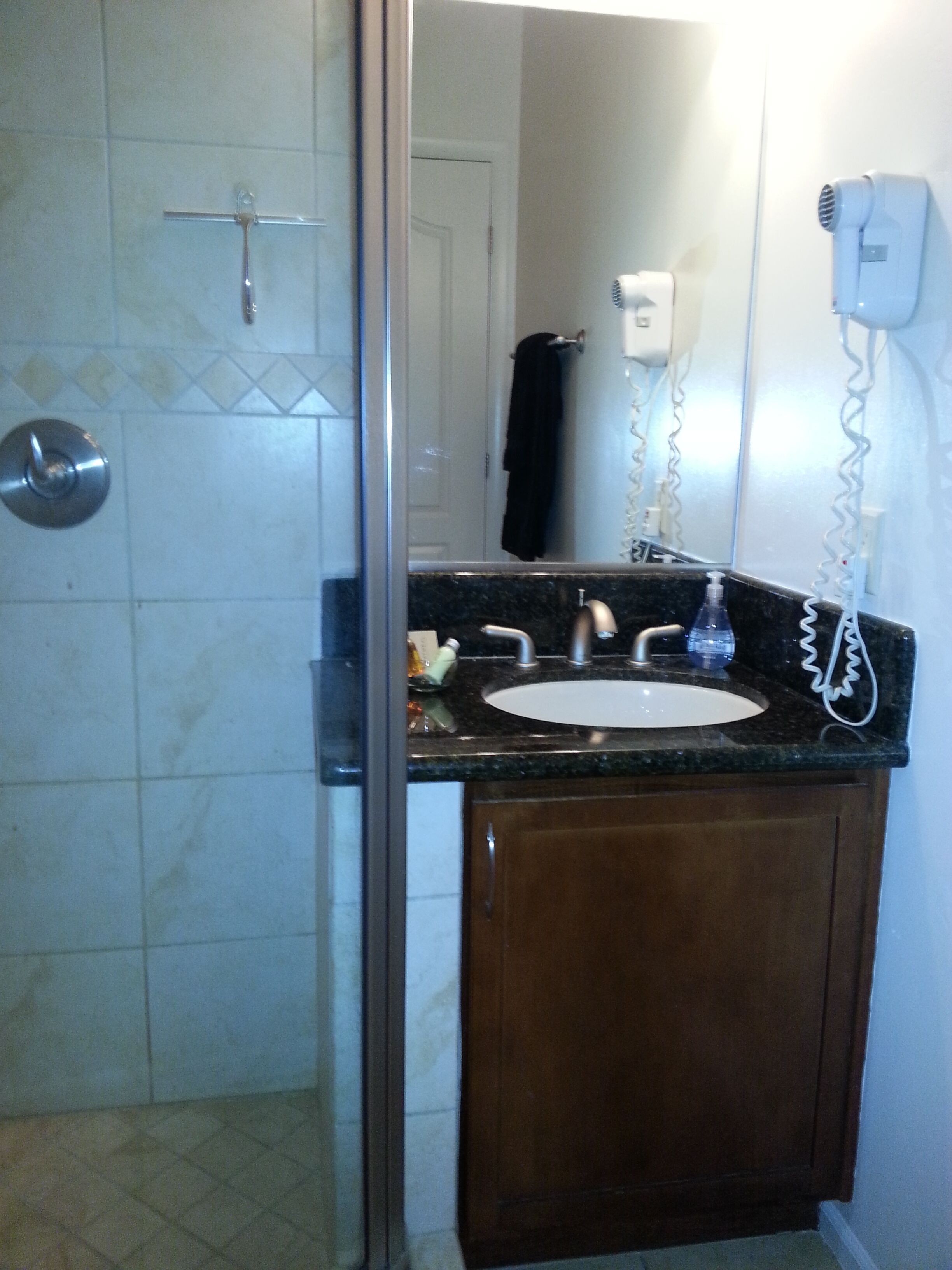 A bathroom with a sink, mirror, and a hairdryer mounted on the wall.