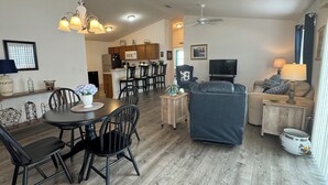 Uma sala de estar moderna com área de jantar, cozinha e televisão.