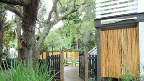 A wooden deck leading to a building with a bamboo fence and a sign that reads "Sweetgrass." - Beautifully decorated 3bdrm/3bath near beach; unique porch with garage doors! (Folly Beach)