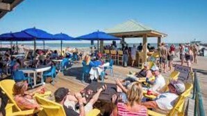 A beachside restaurant with outdoor seating and umbrellas. - Beautifully decorated 3bdrm/3bath near beach; unique porch with garage doors! (Folly Beach)