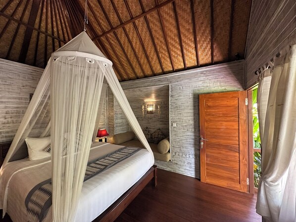 A bedroom with a canopy bed, a wooden door, and a stone wall.