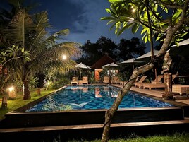 Una piscina al aire libre, sombrillas, sillones reclinables de piscina