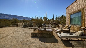 A desert-style outdoor patio with a brick building, hay bales, and outdoor furniture. - Knightly's Ranch Guesthouse  (Tucson)