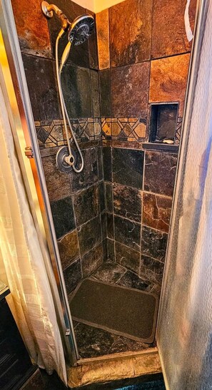 A shower with a handheld showerhead, a glass door, and a tiled wall. - Knightly's Ranch Guesthouse  (Tucson)