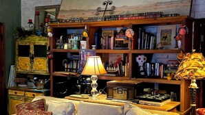 A cozy living room with a sofa, a coffee table, and a bookshelf filled with books and decorative items. - Knightly's Ranch Guesthouse  (Tucson)