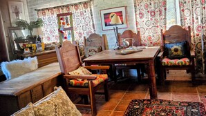 A cozy living room with a wooden sofa, a dining table, and chairs. There are patterned curtains and a rug on the floor. - Knightly's Ranch Guesthouse  (Tucson)