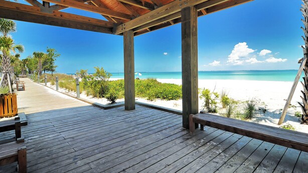 Een houten terras met uitzicht op een strand en de oceaan.