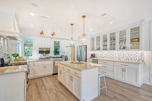A modern kitchen with white cabinetry, a central island, and pendant lighting.