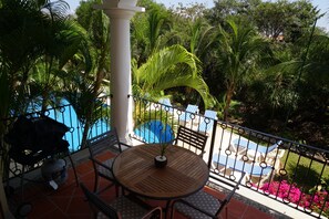 A balcony with a round wooden table, chairs, and a small potted plant.
