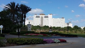 A large, multi-story hotel with a symmetrical facade, surrounded by landscaped gardens and palm trees. - 2 Bed/2 Bath Resort Condo near Disney. (Davenport)