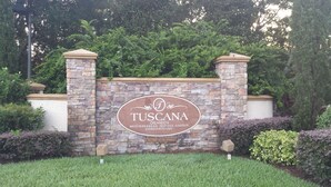 A stone wall with a sign for 'TUSCANA ORLANDO'S MEDITERRANEAN INSPIRED GARDEN CONDOMINIUMS'. - 2 Bed/2 Bath Resort Condo near Disney. (Davenport)