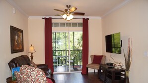 A living room with a sofa, armchair, and a TV on a stand. - 2 Bed/2 Bath Resort Condo near Disney. (Davenport)
