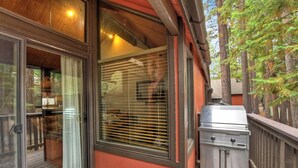 A covered outdoor area with a grill and a sliding glass door leading to a deck.
