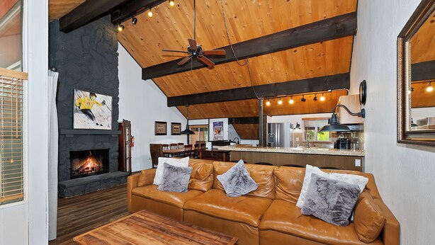 A cozy living room with a leather sofa, a wooden coffee table, a fireplace, and a ceiling fan.