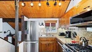 A modern kitchen with stainless steel appliances, wooden cabinets, and a granite countertop.