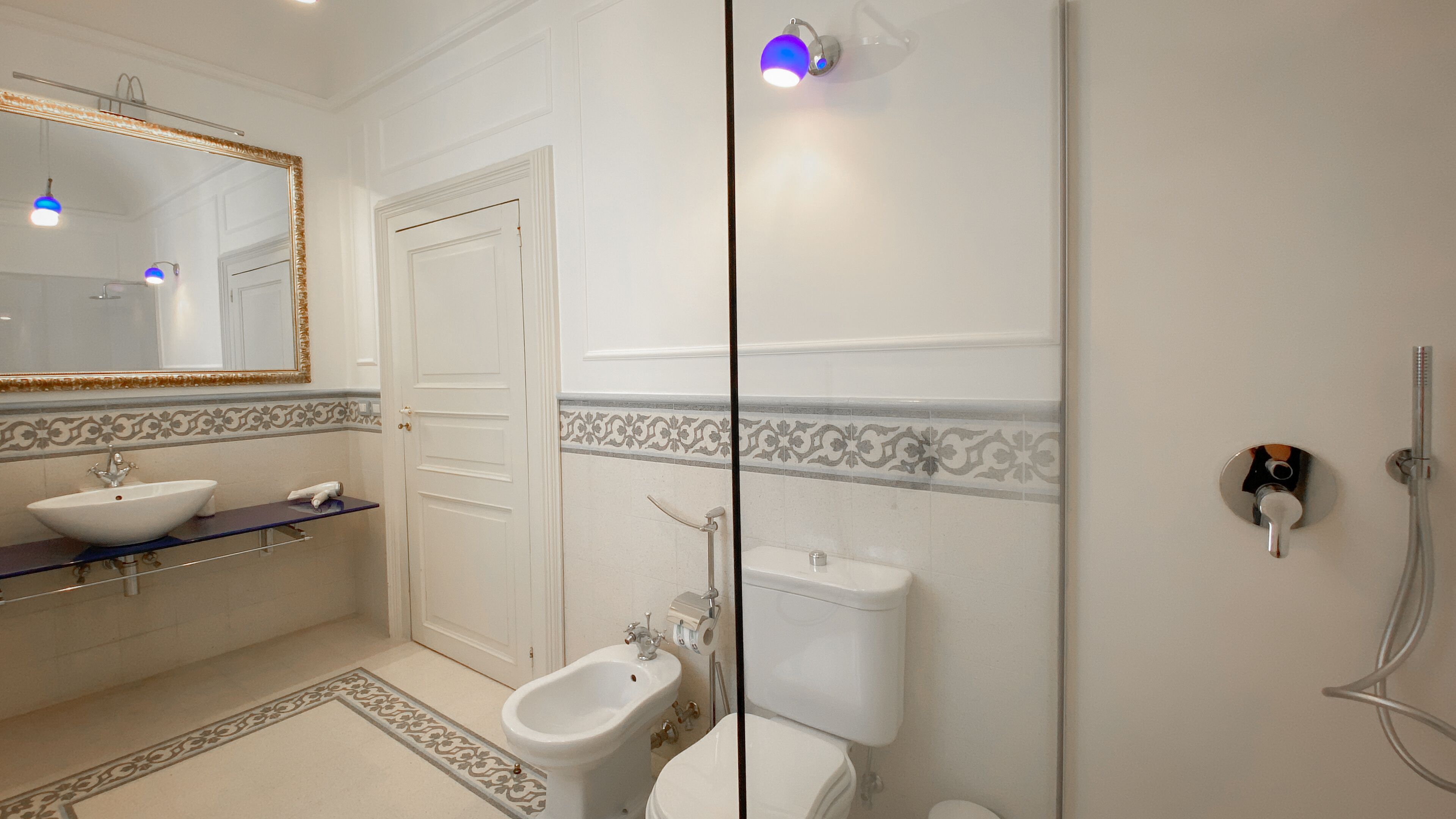 A bathroom with a white sink, bidet, toilet, and a shower.