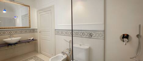 A bathroom with a white sink, bidet, toilet, and a shower.