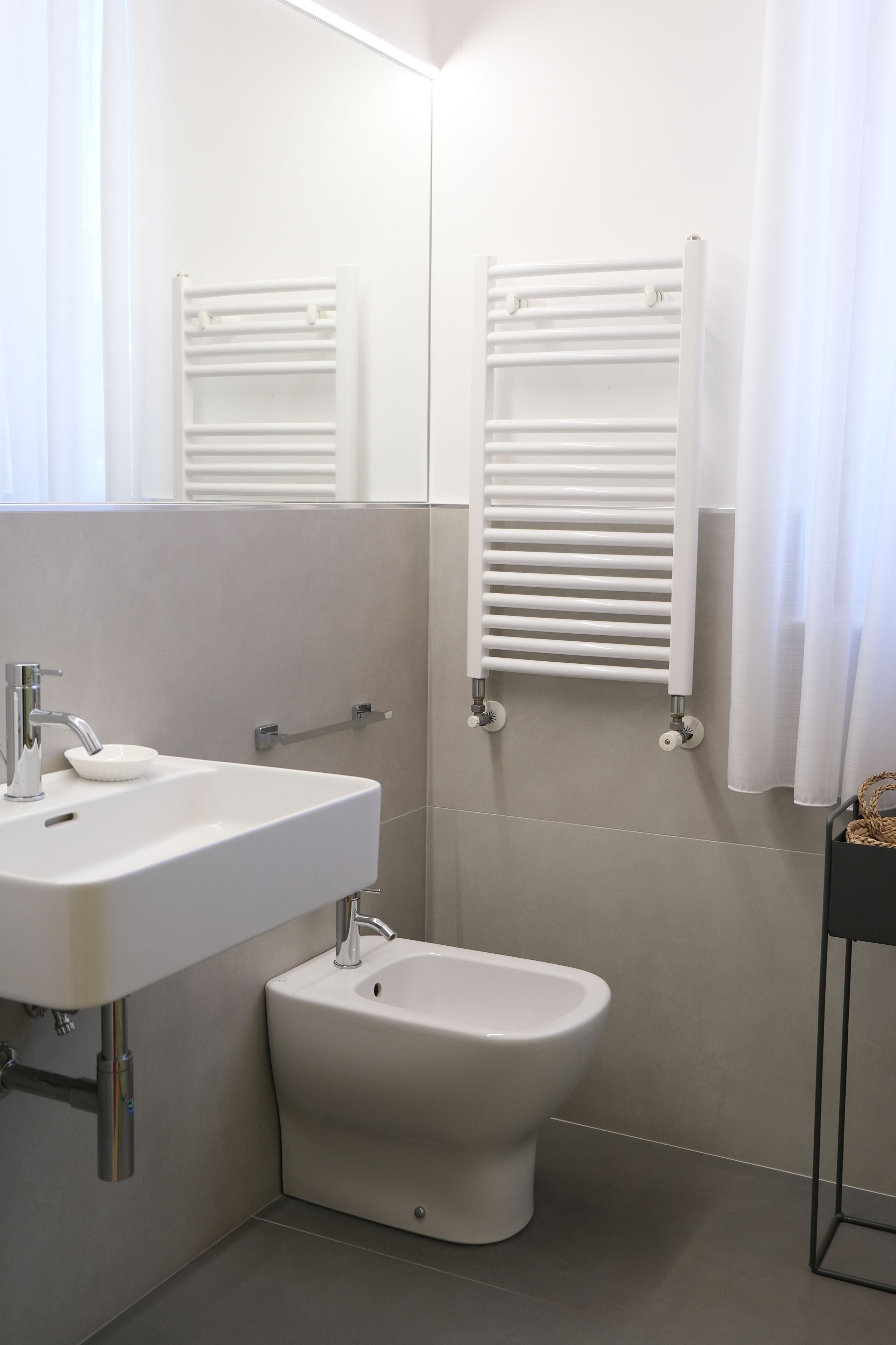 Ein modernes Badezimmer mit Waschbecken, Bidet und Handtuchhaltern.
