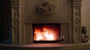 A fireplace with a fire, two cushions, and a fruit basket.