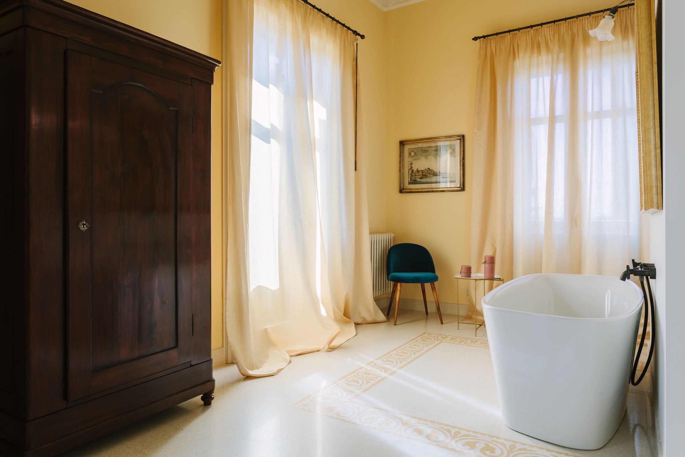 Una habitación con un armario grande de madera, una bañera blanca y cortinas color crema.