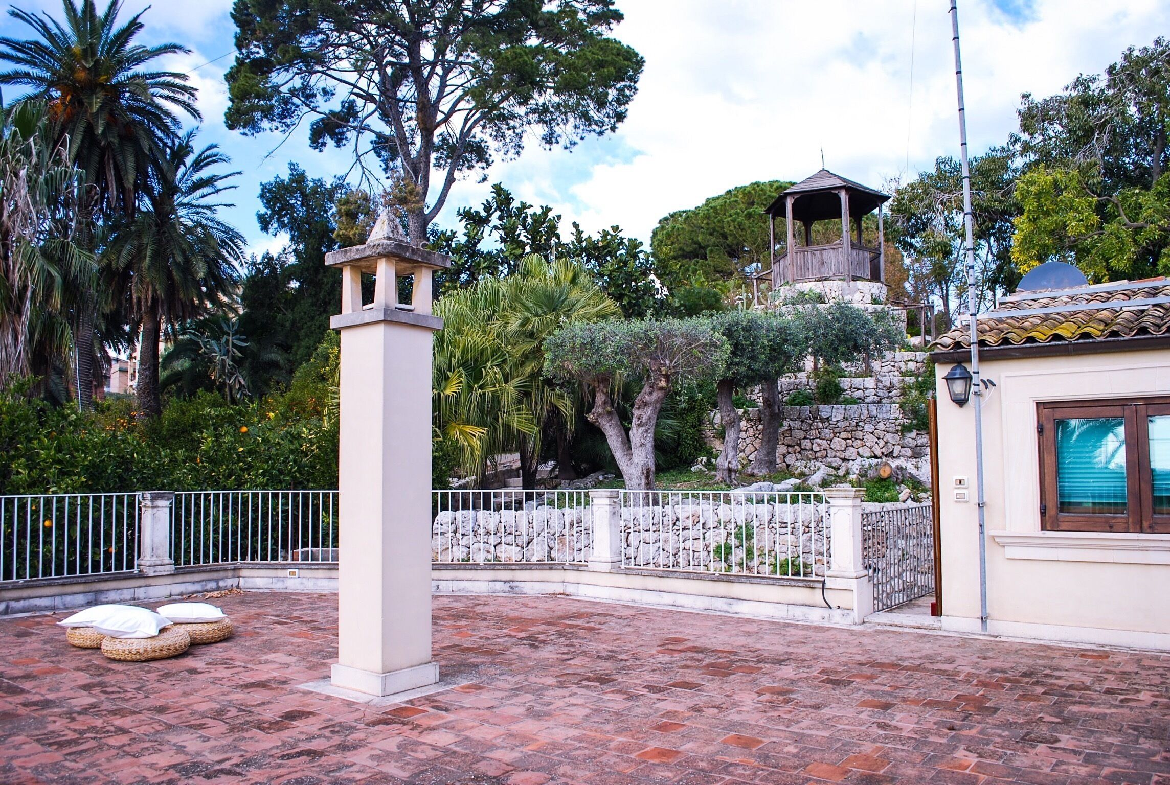 Un patio con pared de piedra, un mirador y suelo de baldosas.