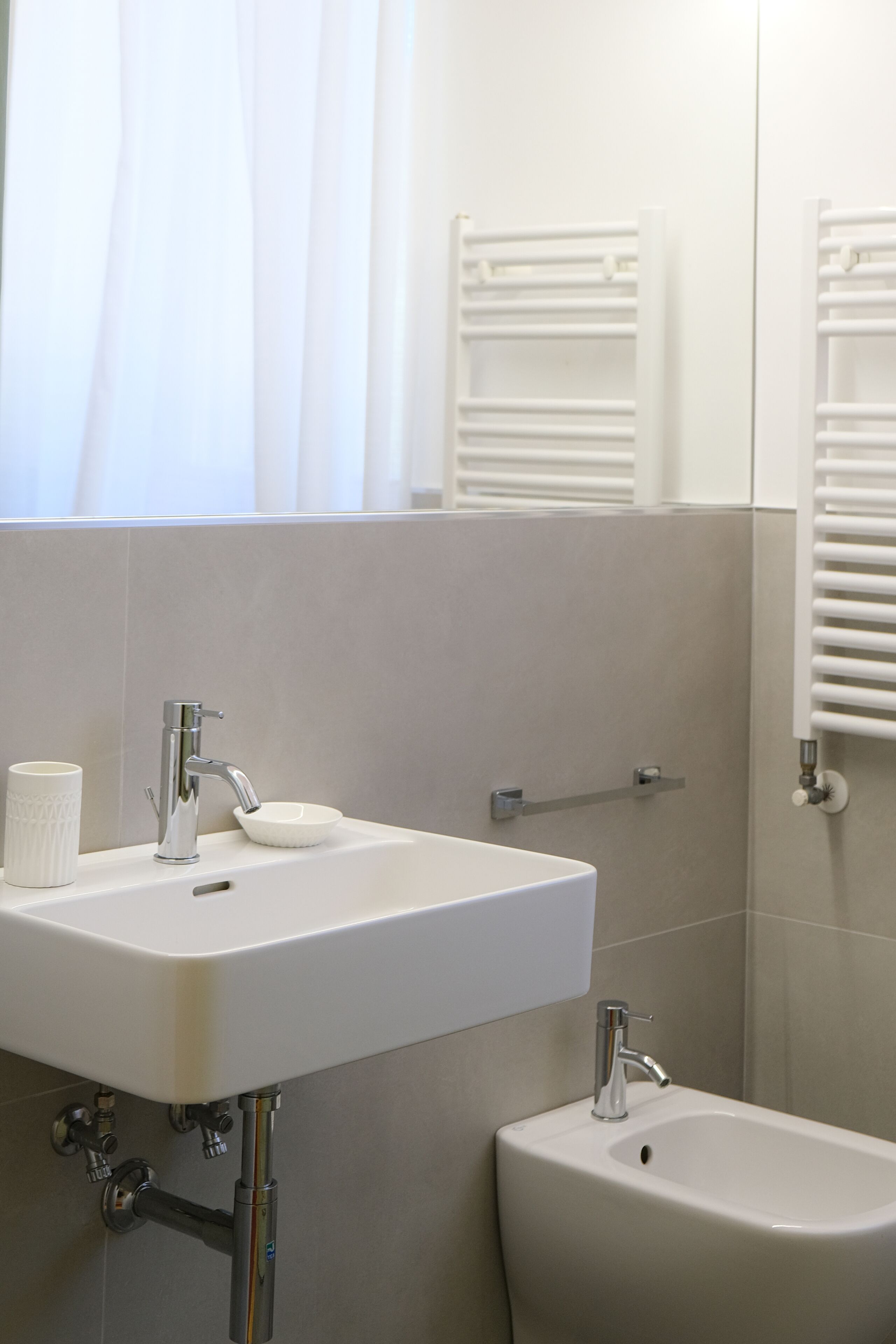 A bathroom with a white sink, a bidet, and a towel rack.