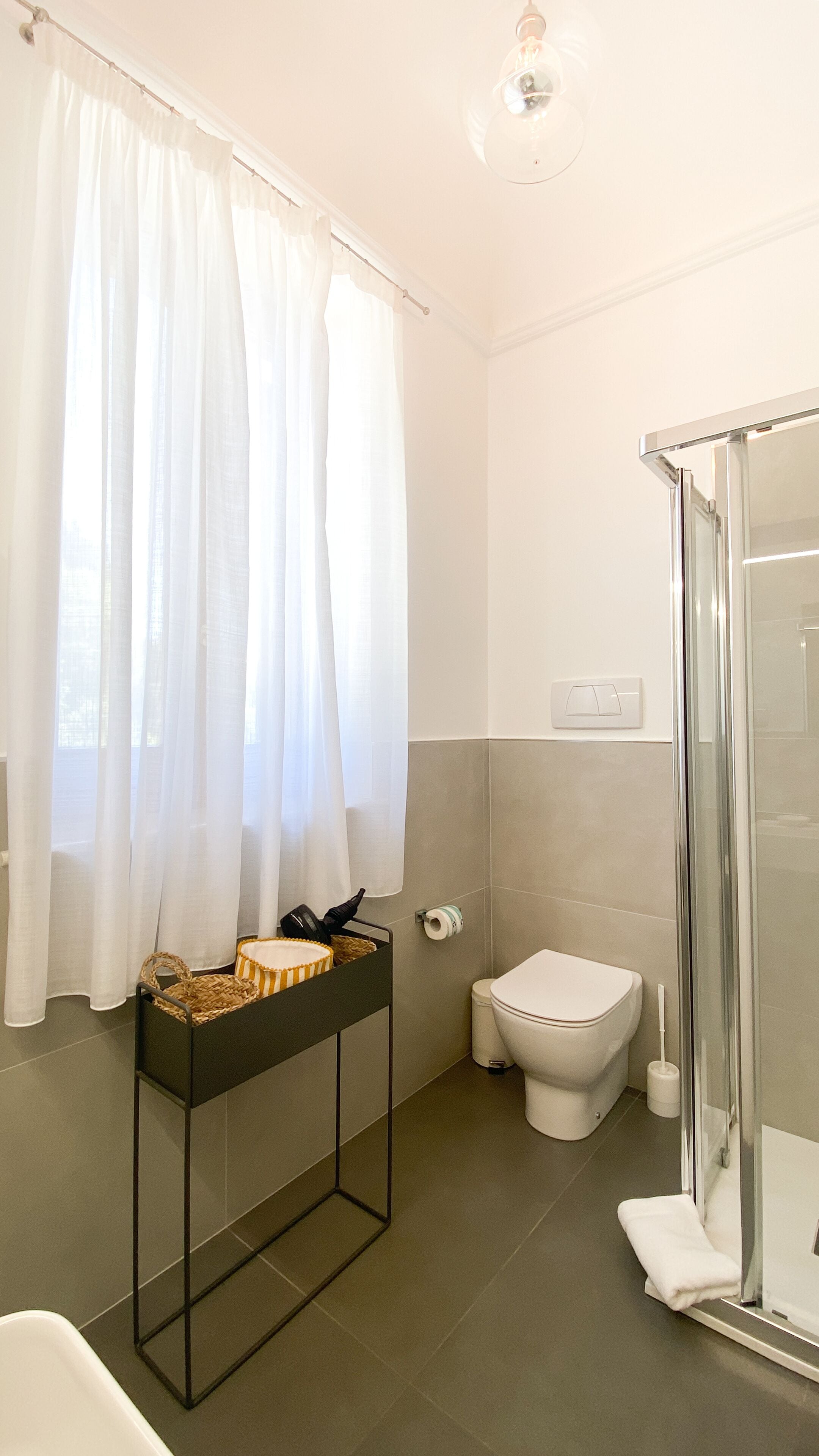A bathroom with a shower, toilet, and a vanity with a basket.