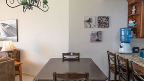 A dining area with a table, chairs, a chandelier, a water dispenser, and wall art.