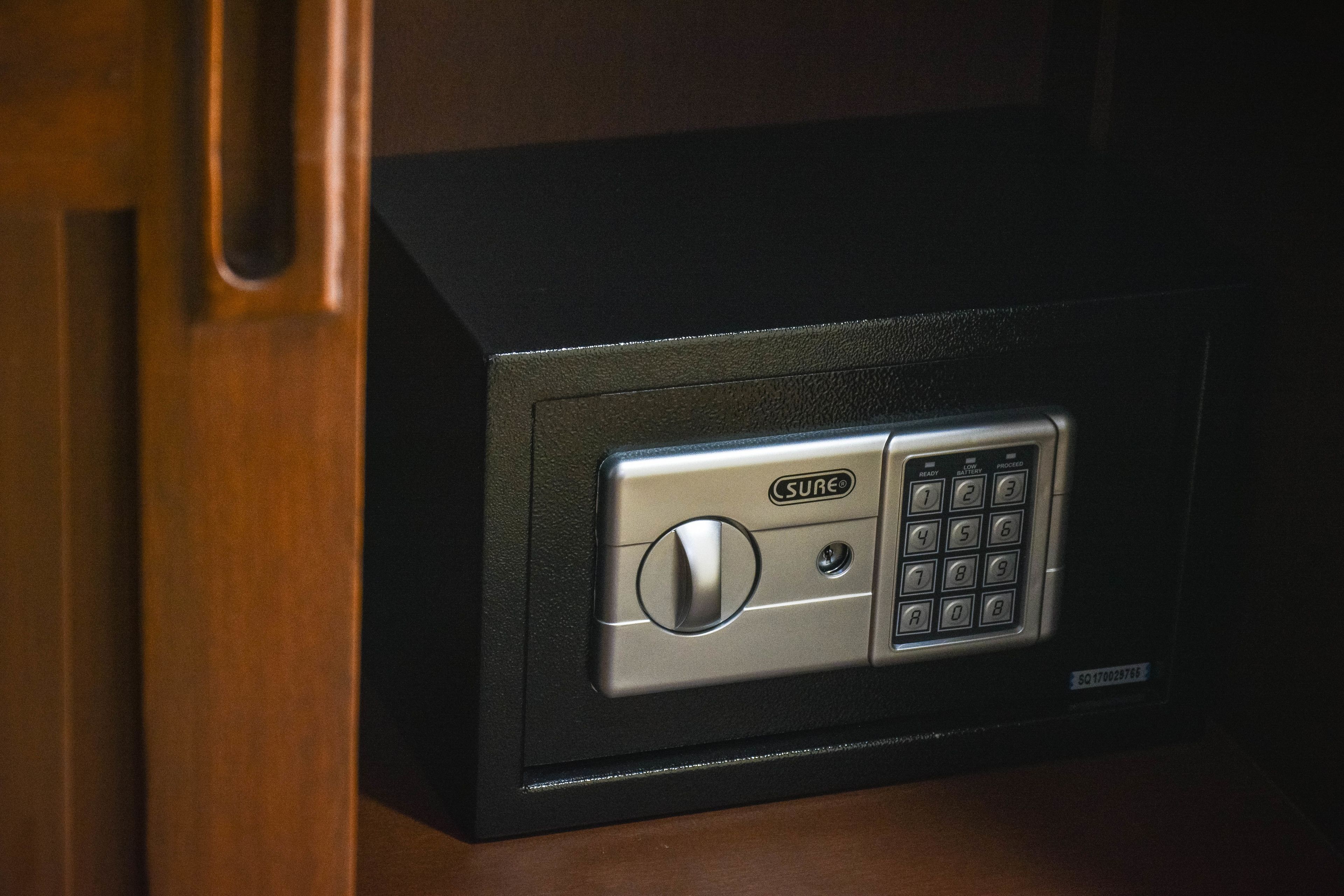 Een zwarte kluis met een keypad en een knop voor het vergrendelen, met de tekst 'SURE'.