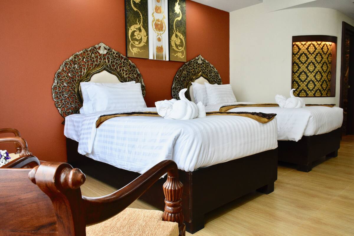 Een hotelkamer met twee bedden, versierde hoofdeinden en een decoratief paneel.