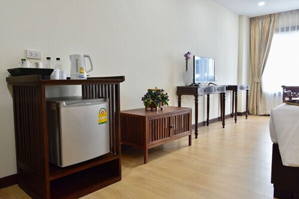 A hotel room with a kitchenette, a television, a small table with a plant, and a bed.