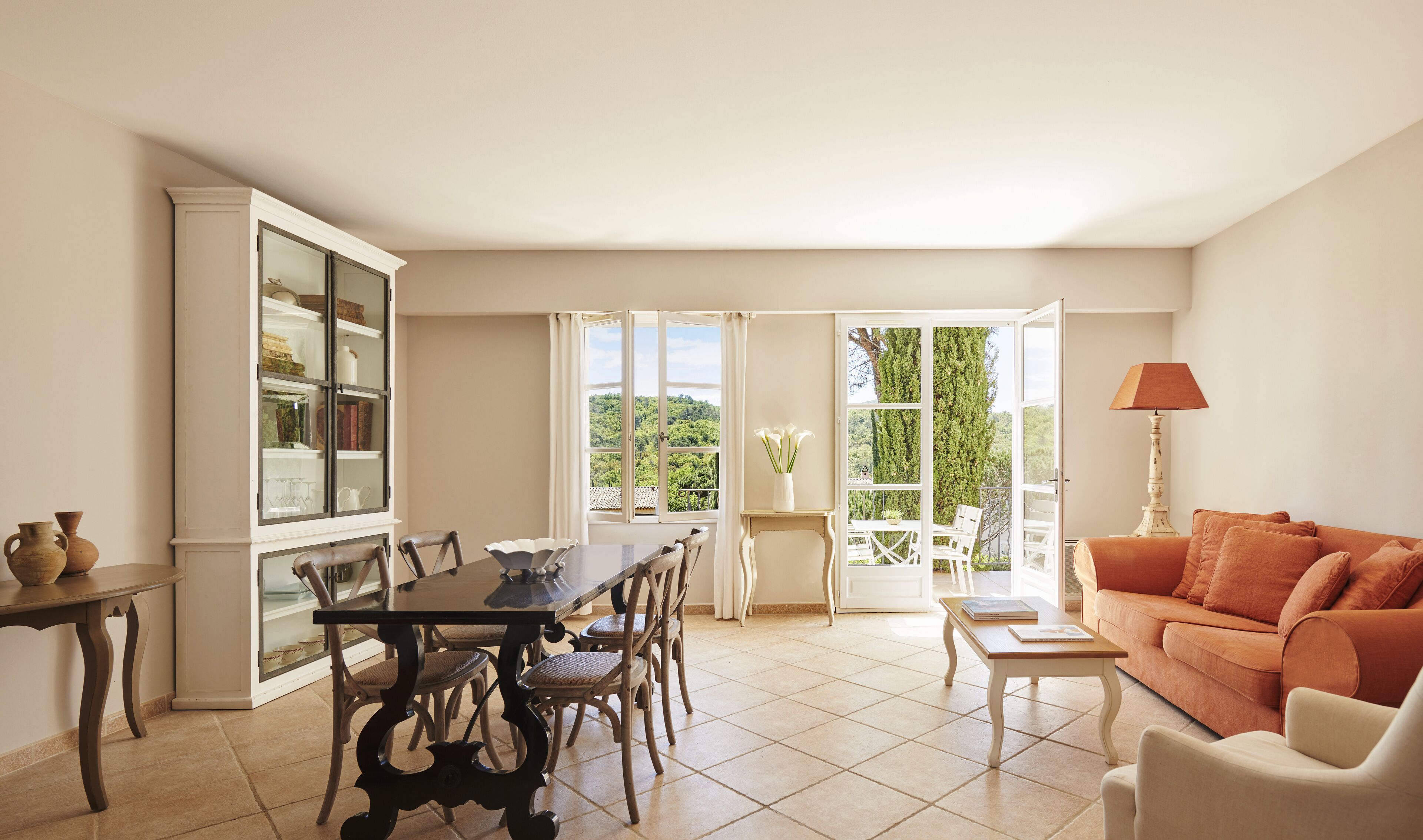 Un amplio salón con una mesa de comedor, sillas, un sofá y una lámpara.