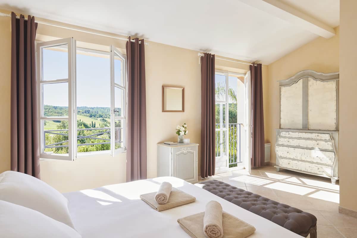 A bedroom with a large bed, a dresser, and a view of the countryside.