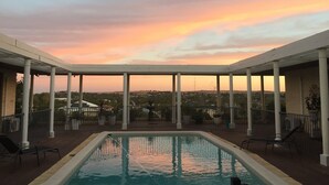 A rooftop pool with a view of a sunset over a cityscape. - Fairway Manor Accommodation (Northam)