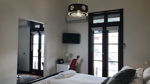A hotel room with a large bed, a desk, a chair, a TV, and a balcony with a view. - Fairway Manor Accommodation (Northam)